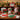 Container of multicolored pens with Christmas-themed designs on a table.
