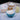 Blue bowl with eggnog, graham crackers, and a bottle of milk on a white surface.
