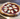 Small pizza with tomato sauce, cheese, and basil on a wooden surface