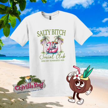 A white t-shirt with a graphic print that includes a palm tree, a flamingo, a cocktail, and the text 'SALTY BITCH SOCIAL CLUB' along with the phrase 'KISS MY SUNBACKED ASS' in a vibrant beach scene.