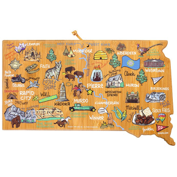 A bamboo cutting board shaped like South Dakota state with colorful, hand-drawn artwork featuring landmarks and text.