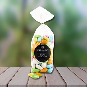 Bag of colorful almonds with 'Abdalilah' branding on a wooden surface.