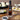 Olivelle toasted sesame oil bottle on a wooden table with food items like sushi and dumplings.