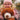 Child wearing pink glasses and a pink hat, holding a brown bubba amber teddy bear outdoors.
