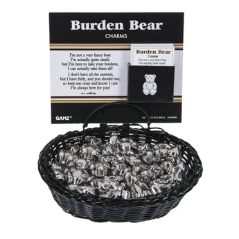 A black wicker basket filled with silver ZINC Burden Bear charms, shown in front of its black and white branded card packaging.
