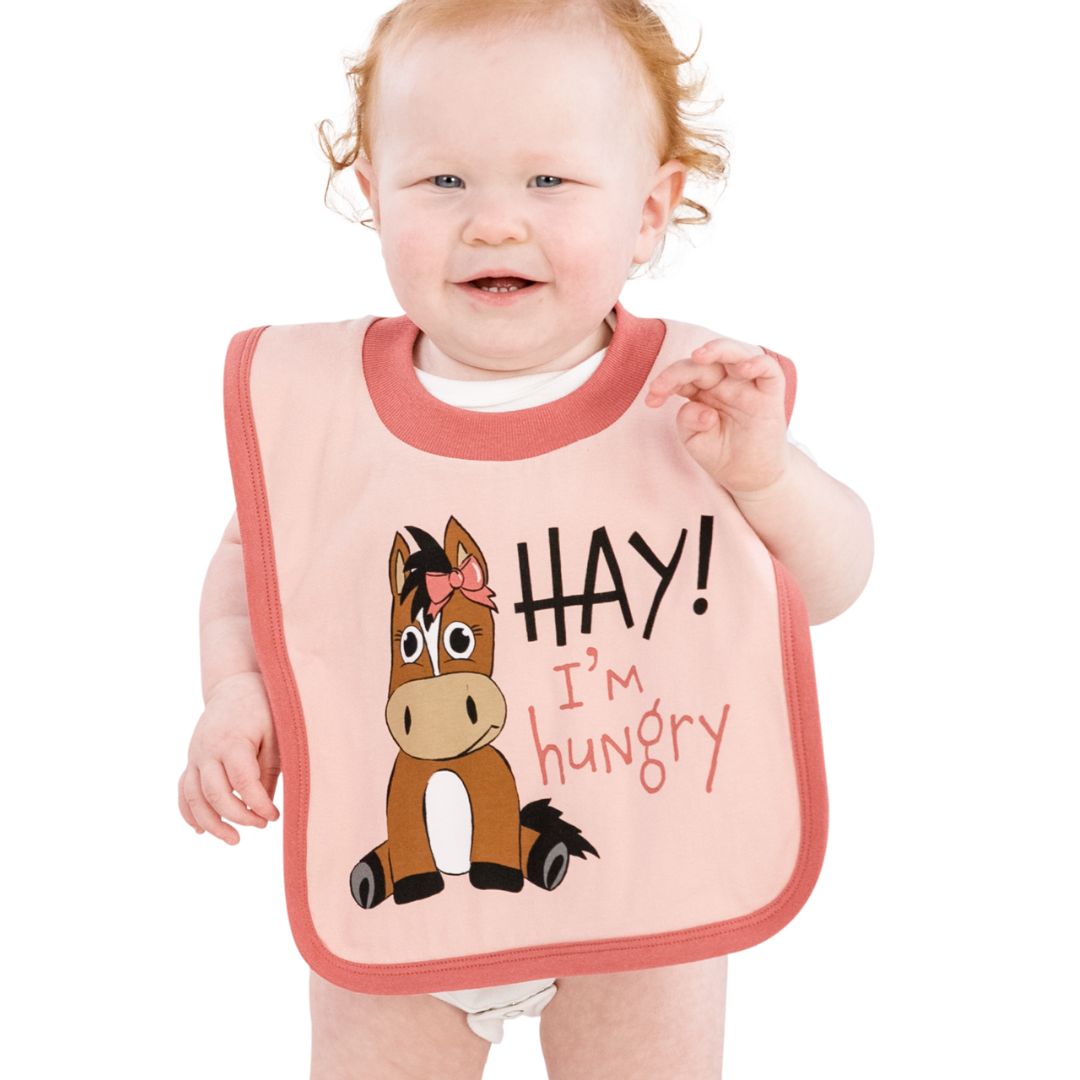 Infant bib in Evening Sand Pink with a horse design and 'Hay, I'm Hungry' text, made from 100% combed cotton, featuring easy on & off elastic neck and contrasting trim