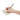 Hand holding a pen over a piece of paper with a grocery list on a white background