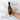 A hand holds a bottle of Olivelle Roasted Shallot Extra Virgin Olive Oil against a white marble background, surrounded by text callouts describing its production and flavor.