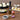 Olivelle Roasted Shallot oil bottle on a wooden table with sushi, dumplings, and shallots.