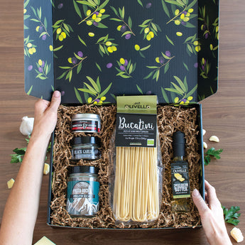 Gift box with pasta, olive oil, salt and dipper on a wooden surface