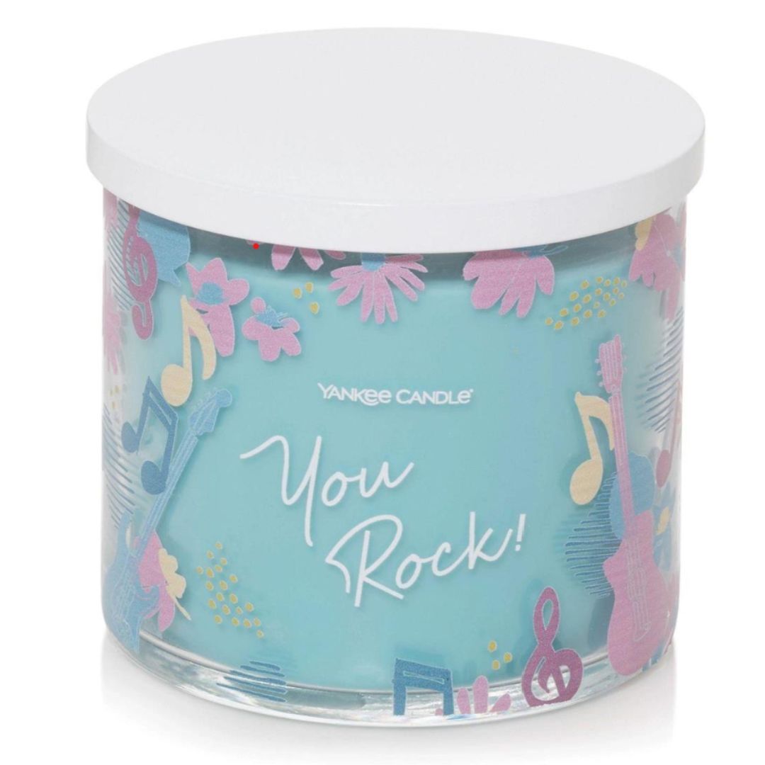 'You Rock!' labeled Orange & Amber 3-Wick Candle in a glass jar with a unique beach-themed label and embossed metal lid, evoking warm summer sunshine.