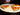 Three slices of pizza reheating in the oven on a pizza baking tray.
