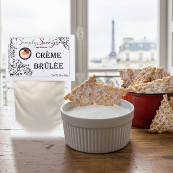 Creme brulee packaging with a bowl of creme brulee and cookies on a wooden surface.
