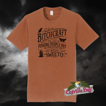 Funny witch t-shirt - Texas Orange Bitchcraft graphic tee with gothic text design: "The art of pissing people off and smiling sweetly."