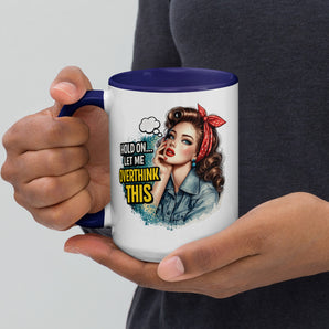 Person holding a mug with a graphic design of a woman and text 'Hold on, let me overthink this' against a plain background.