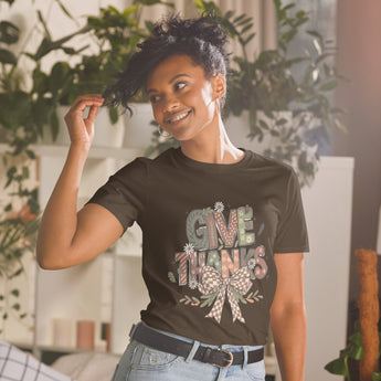 Woman wearing a 'Give Thanks' t-shirt in a home setting with plants.