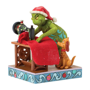 Jim Shore Dr. Seuss Grinch Figurine sewing Santa suit with Max watching beside, hand-painted with real fabric details and folk-art patterns.