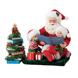 Possible Dreams Reading is a Gift Santa figurine featuring Santa reading The Night Before Christmas to two children beside a Christmas tree made from stacked books and holiday garland.
