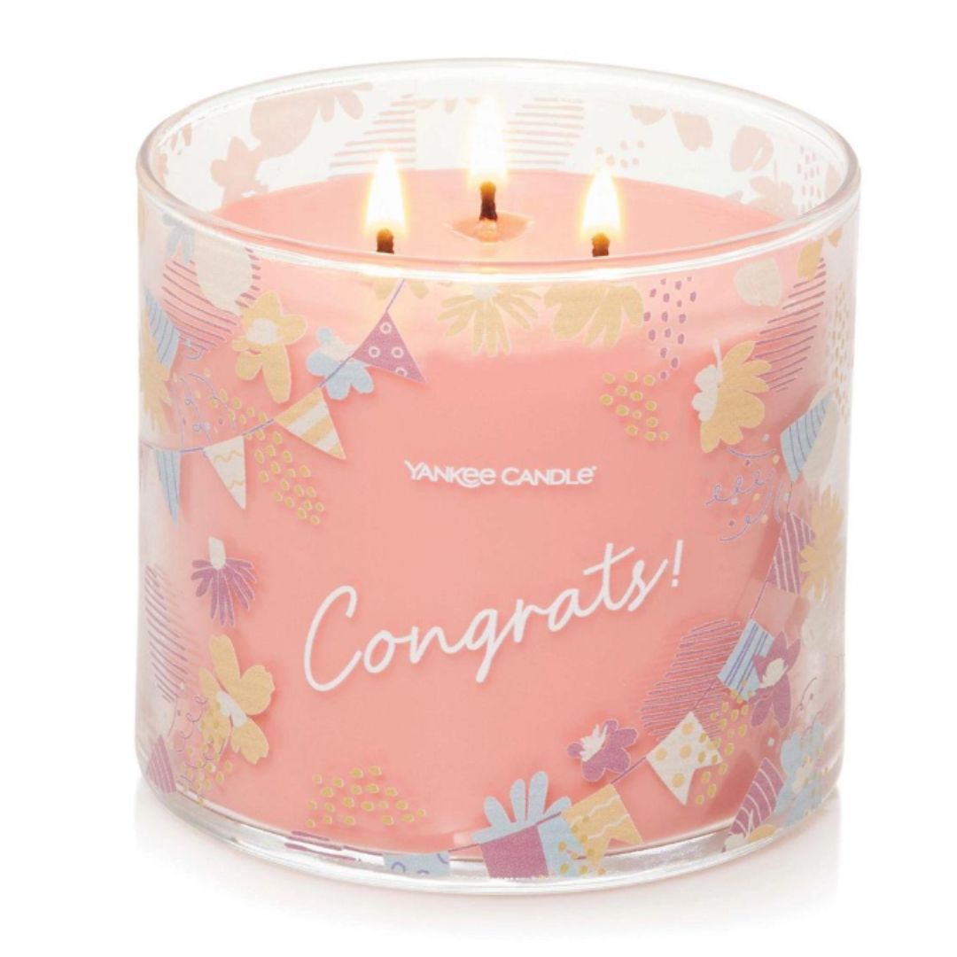 'Congrats!' White Strawberry Bellini 3-Wick Candle in a glass jar, decorated with pennants and flowers label, emitting a sweet, sophisticated brunch-like fragrance.