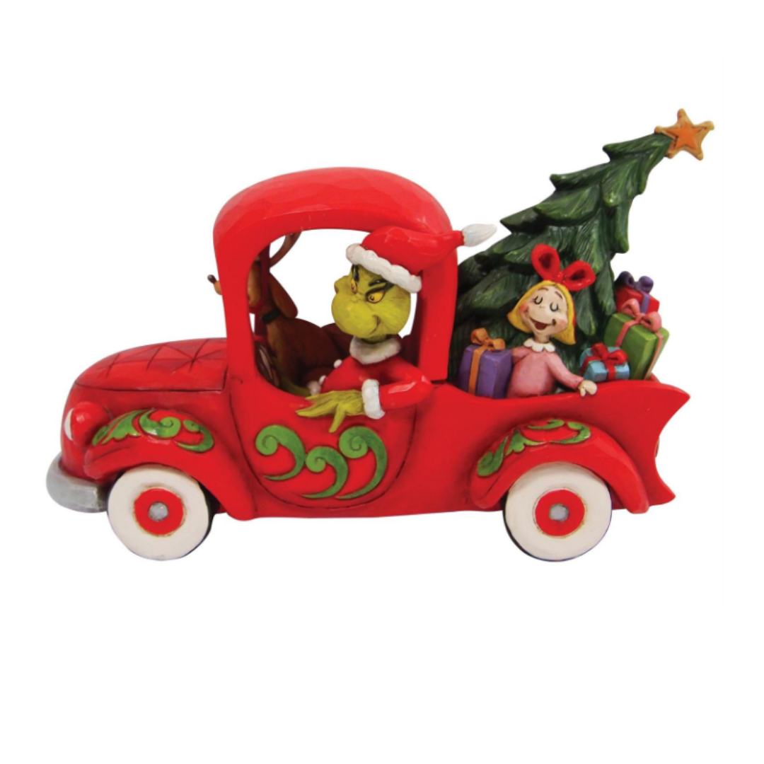 Grinch driving a red truck with Max in the passenger seat and Cindy Lou in the back with the Christmas Tree and presents saving Christmas. A Jim Shore Figurine.
