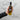 Bottle of Olivelle Maple-wood smoked bacon olive oil held by a hand on a marble background with text about the product.