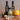 Three bottles of Olivelle kitchen oil and vinegar arranged on a wooden surface with fresh and dried fruit props: two tall dark bottles labeled Harvest Fig and Blood Orange, a smaller clear bottle in front, and whole figs, dried orange slices, and an orange nearby.