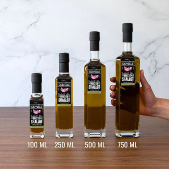 Set of four roasted shallot olive oil bottles with varying capacities on a wooden surface.