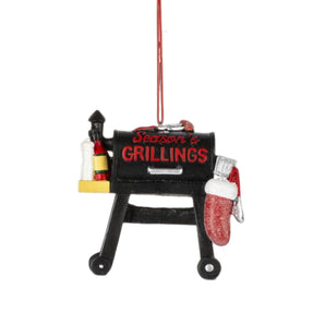 Season's Grillings BBQ ornament shaped like a grill with sauces and Christmas mitt