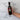 Bottle of Olivelle sun-dried tomato balsamic held by a hand on a marble surface with text highlighting its features.