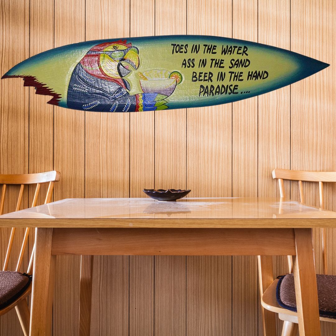 vibrant surfboard-shaped sign with parrot holding a margarita, with the phrase 'Toes in the water, ass in the sand, beer in the hand, paradise...'