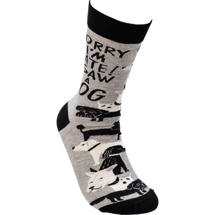 Grey and black 'Sorry I'm Late I Saw a Dog' crew socks with woven dog designs and saying by Johnny Carrillo.